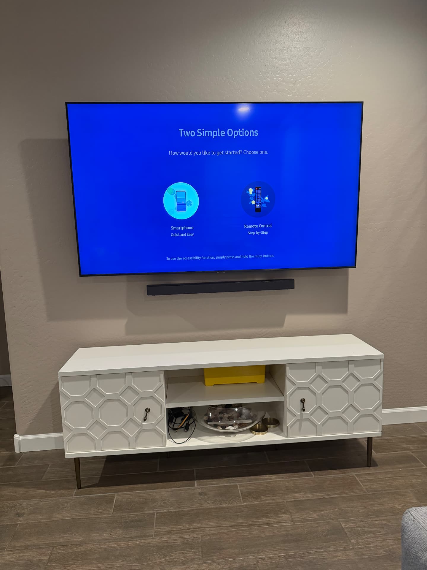 TV and soundbar mounted above a media cabinet with concealed wiring