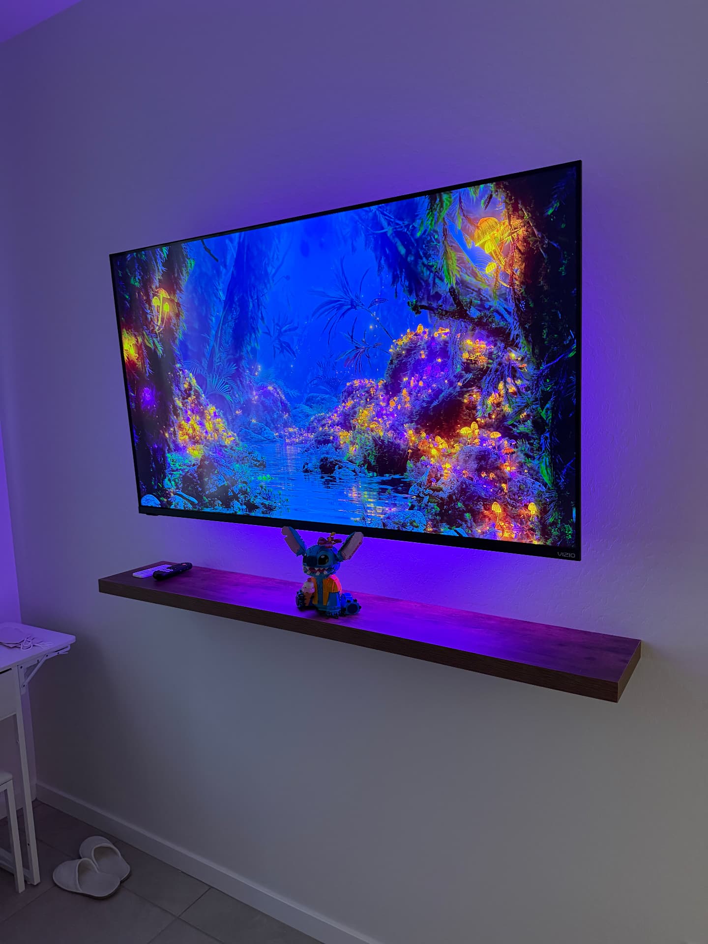 TV mounted above a floating shelf with backlighting and hidden wires