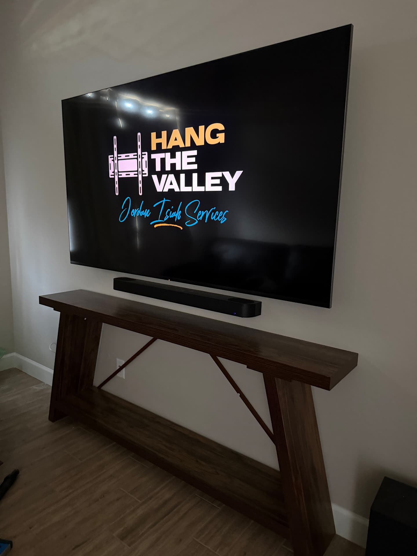 Large TV mounted flush on a living room wall above a wood console table